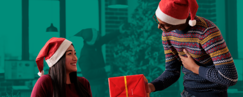mężczyzna przekazuje prezent kobiecie oboje ubrani w czapkach Świętego Mikołaja