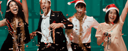 dwóch mężczyzn i dwie kobiety tańczący w czapkach Mikołaja na świątecznym przyjęciu
