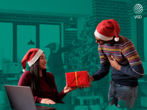 a man giving over a gift to a woman having both christmas hats on