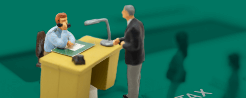 miniaturowy mężczyzna stoi przy biurku w urzędzie skarbowym i rozmawia z urzędnikiem na temat podatków